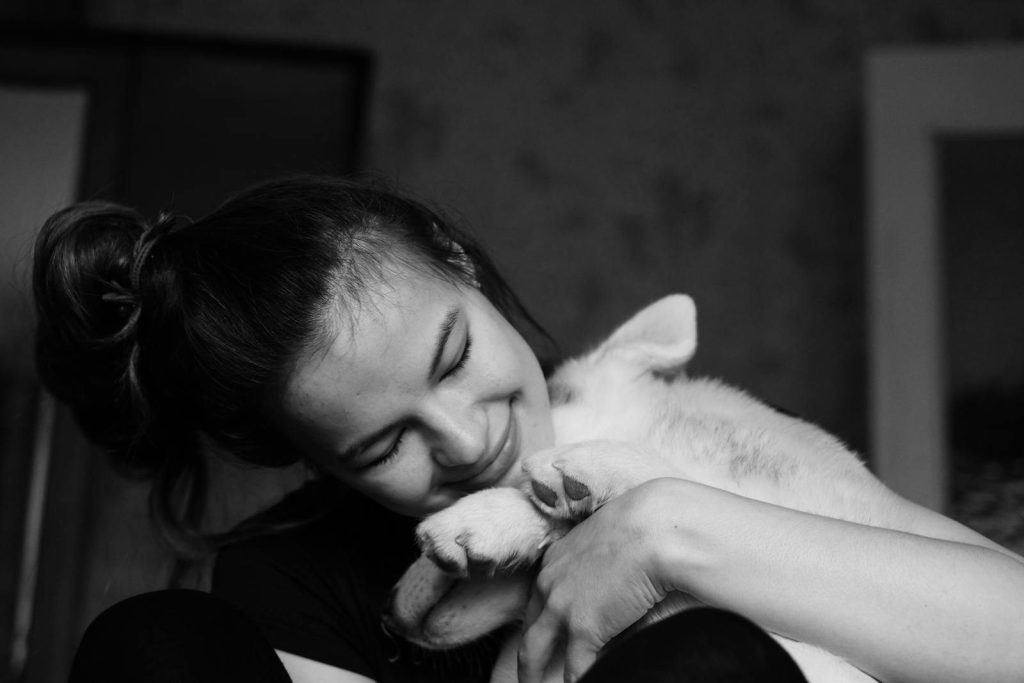 A woman embraces her dog lovingly in a black and white photo, capturing a tender moment.