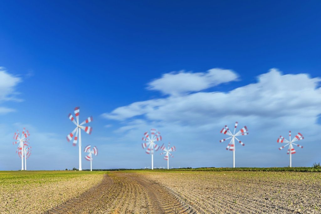 A dirt road with a row of windmills in the distance