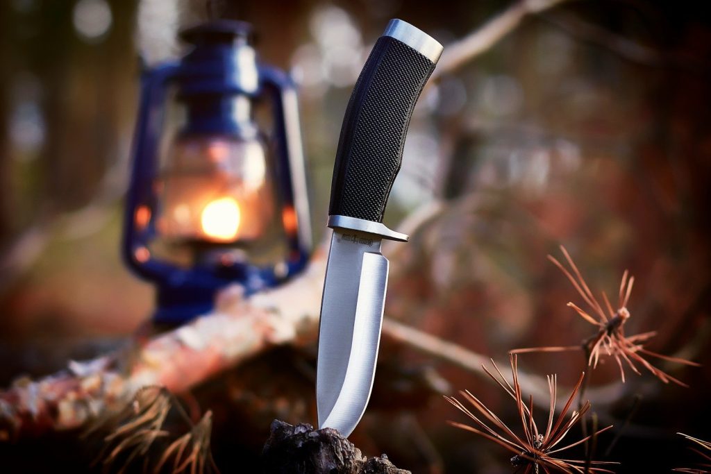 black and gray knife dip-in brown wood near blue lantern