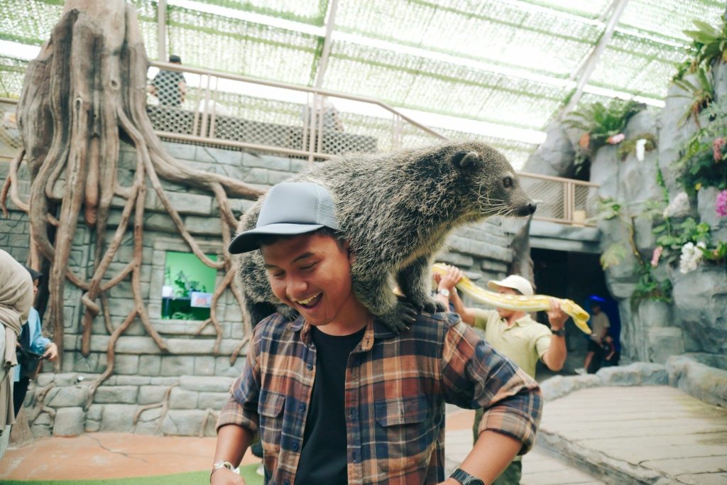 Man with animal on his shoulders at zoo