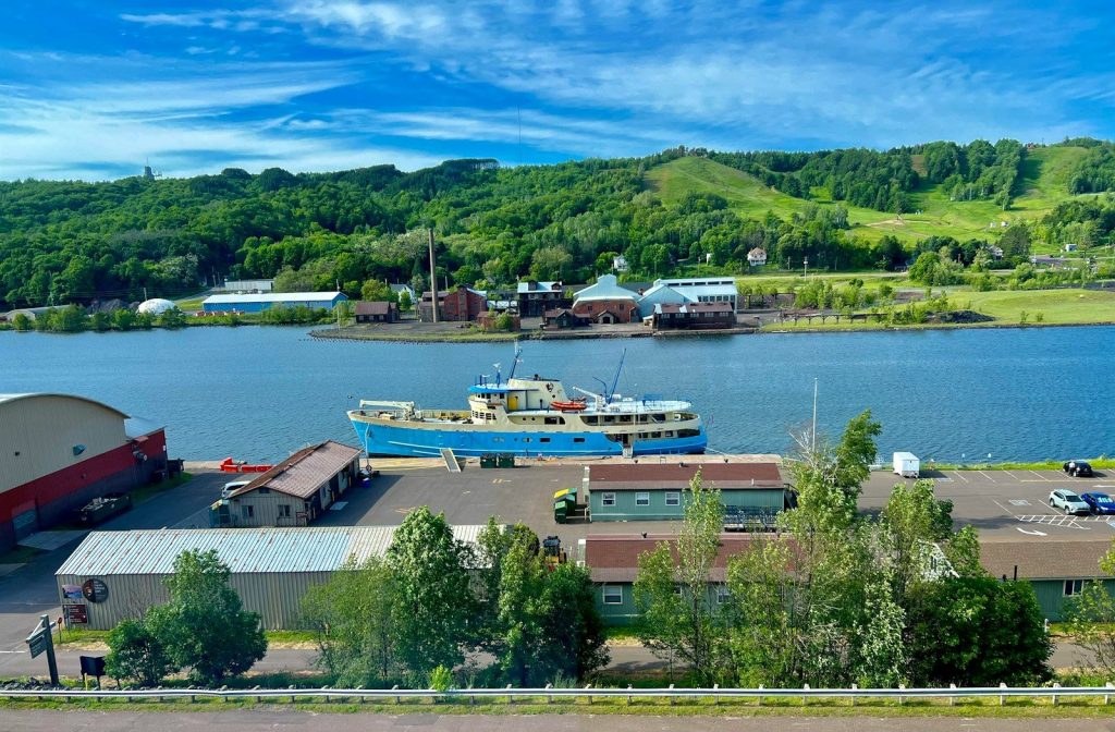 A large body of water sitting next to a lush green hillside