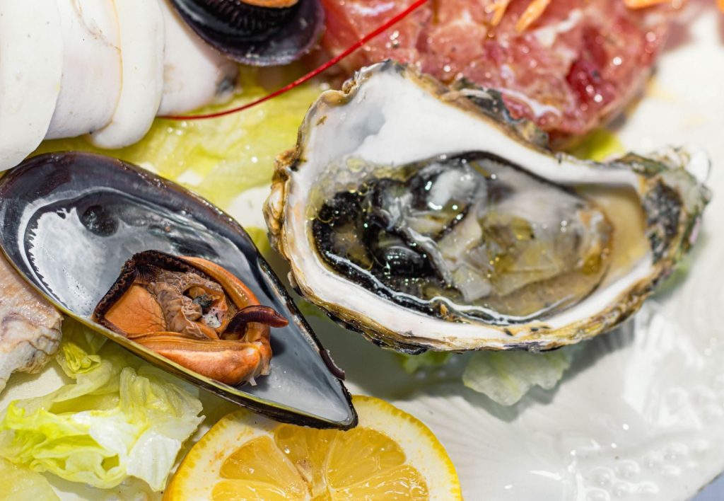 Close-up of a gourmet seafood platter with fresh oysters, mussels, and lemon slices.