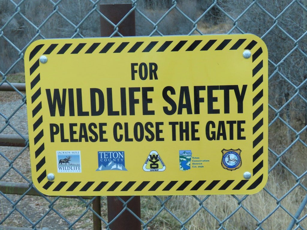 a yellow and black sign on a chain link fence