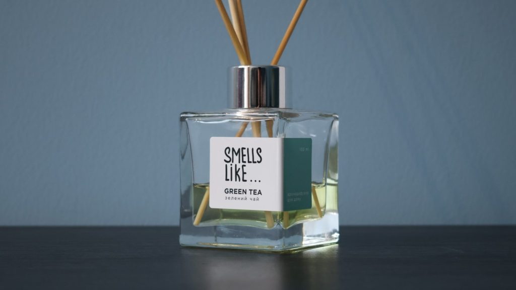 A glass bottle with reeds in it sitting on a table