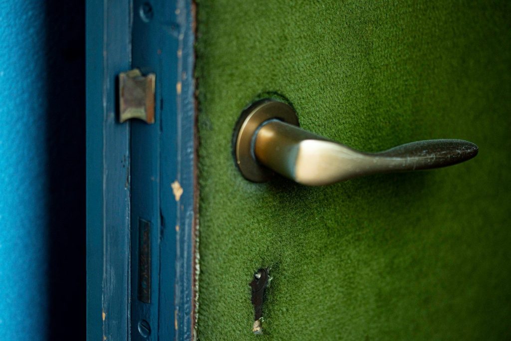 silver door lever on green wooden door