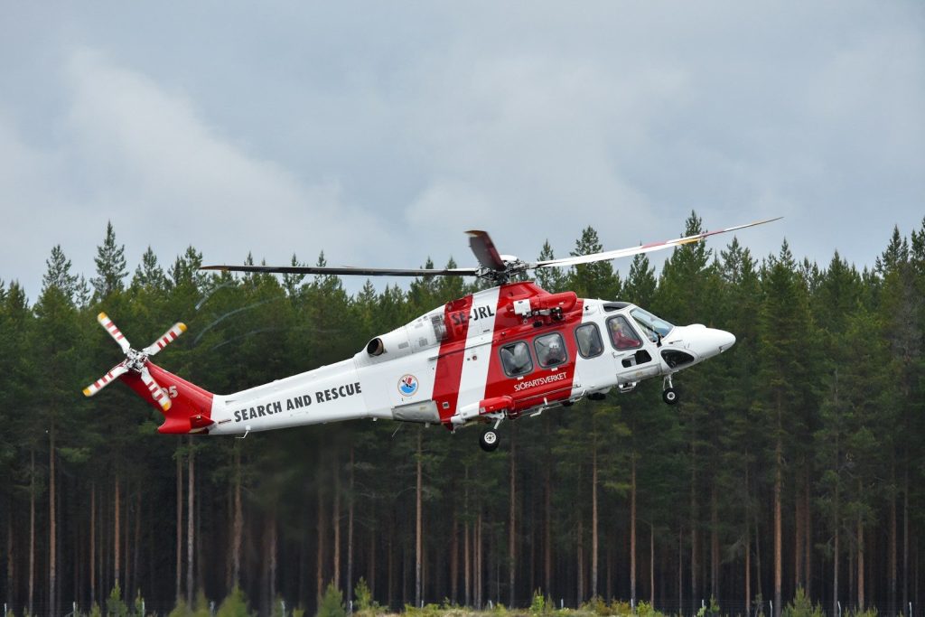 Search and rescue helicopter flying above trees.
