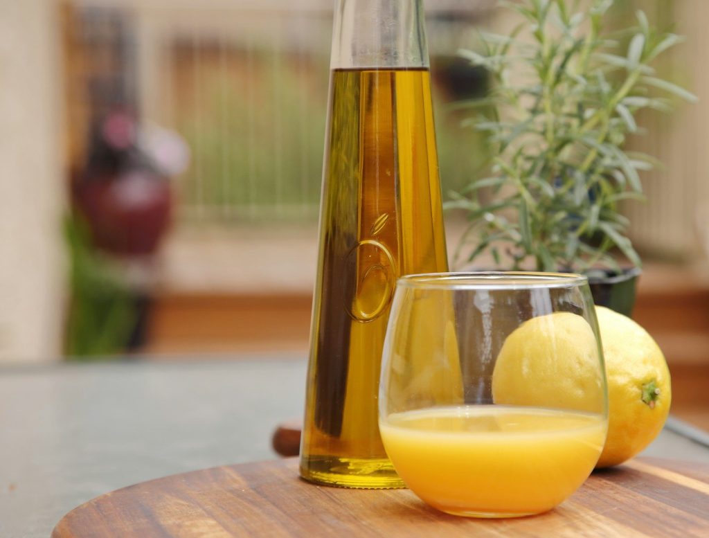 Fresh olive oil, orange juice, lemon, and rosemary outdoors.