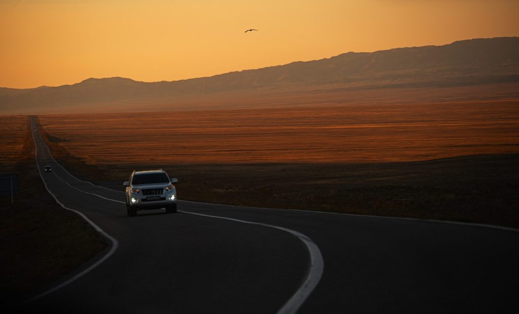 A car drives on a road at sunset.