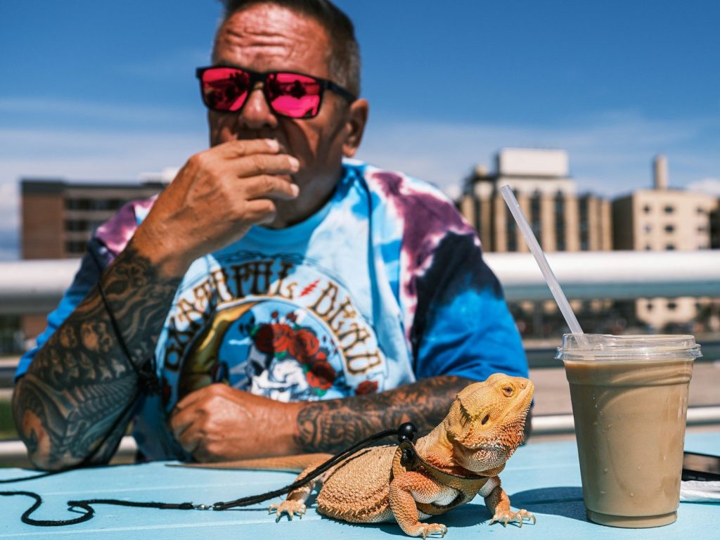 Man with sunglasses and lizard at outdoor table
