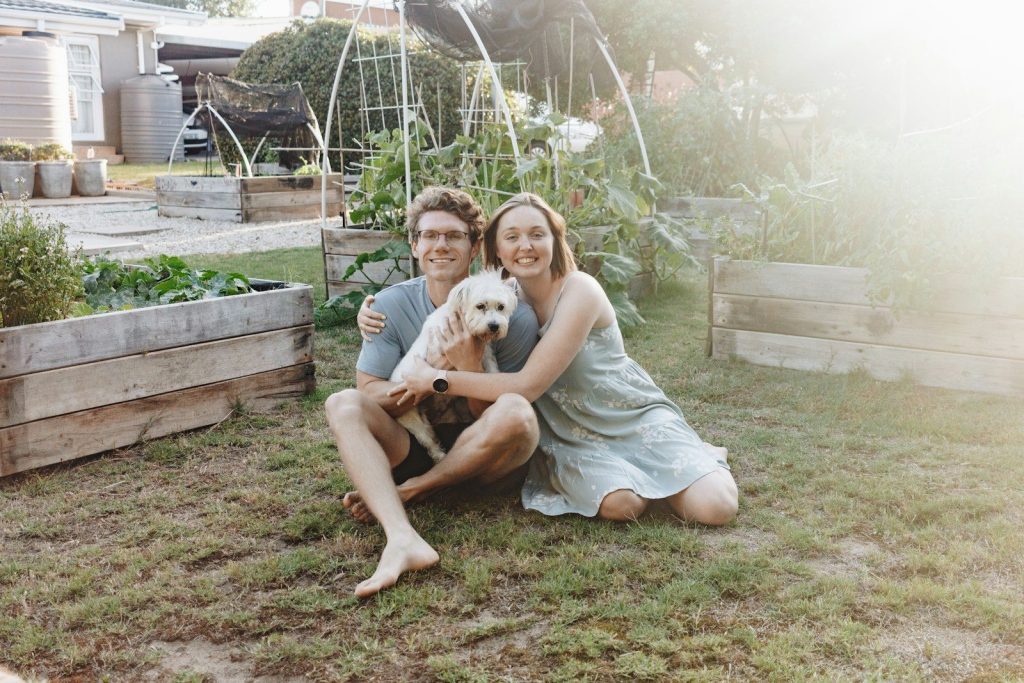 woman in gray tank top sitting on brown wooden bench beside white short coated dog