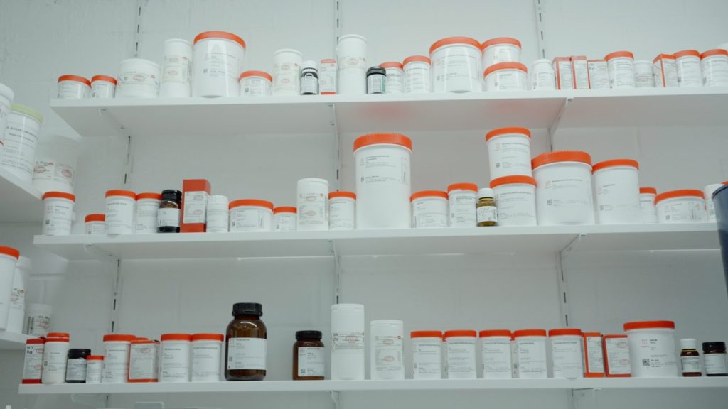 a shelf filled with lots of white and orange medicine bottles