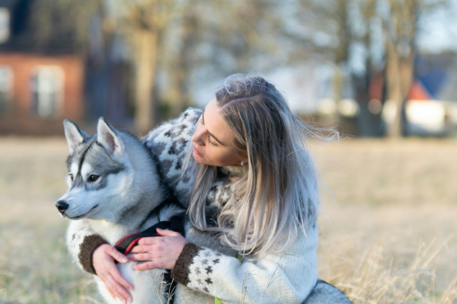 A woman is holding a dog in a field