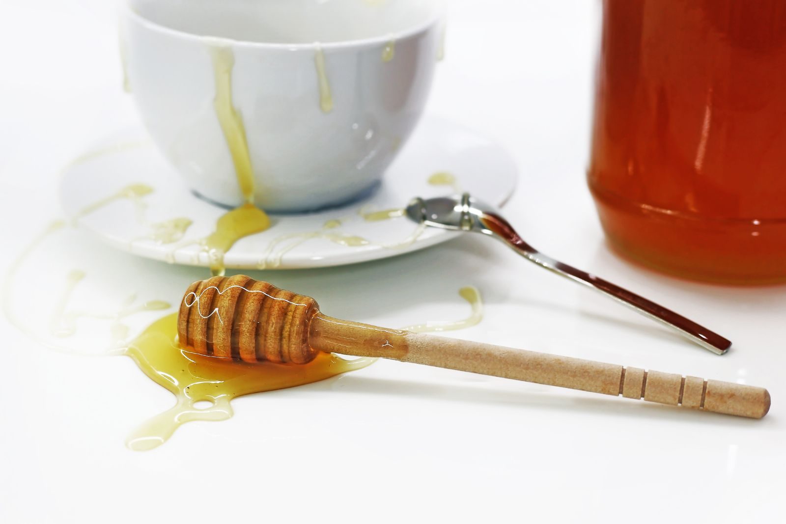 Close-up of honey dripping from a wooden dipper and bowl, showcasing sweet indulgence.