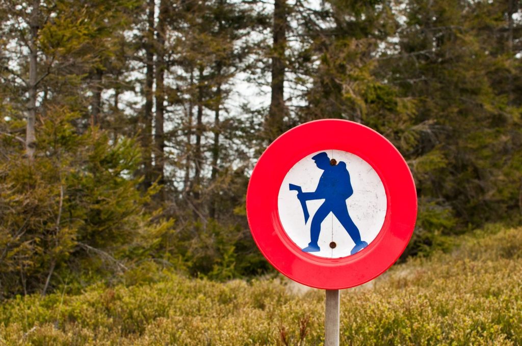 A forest scene featuring a red circle hiking prohibition sign indicating restricted access.