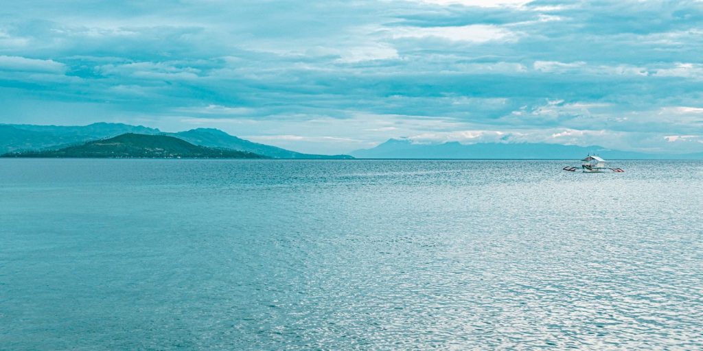 Peaceful seascape in Moalboal with a lone boat on the ocean and a scenic horizon.