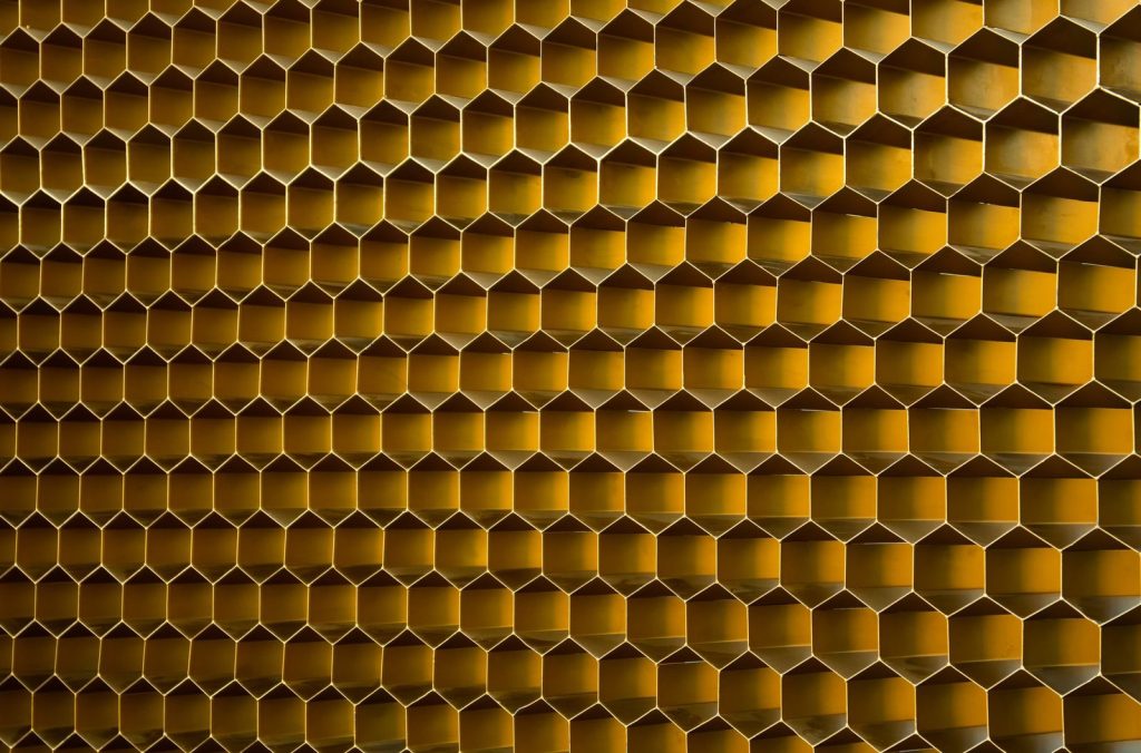 Close-up of a modern hexagonal honeycomb pattern with a warm golden tone.