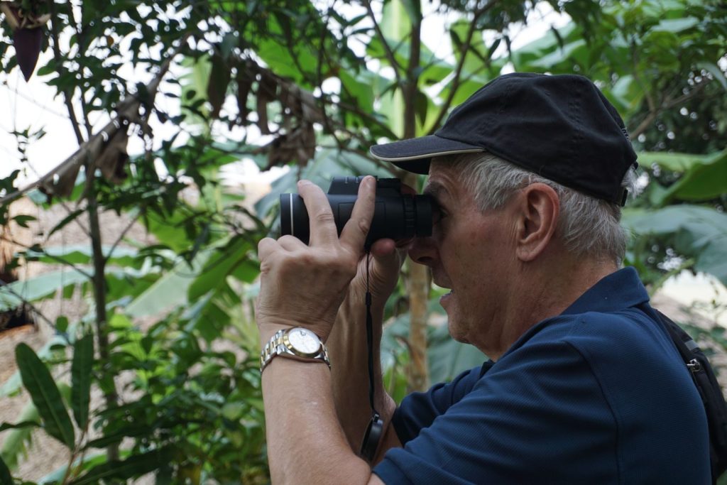 A man capturing the rich greenery of Ha Giang, Vietnam on a camera.