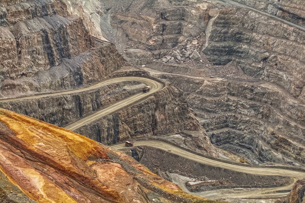 Dramatic aerial shot of winding roads in a massive open-pit mine, showcasing earth textures.