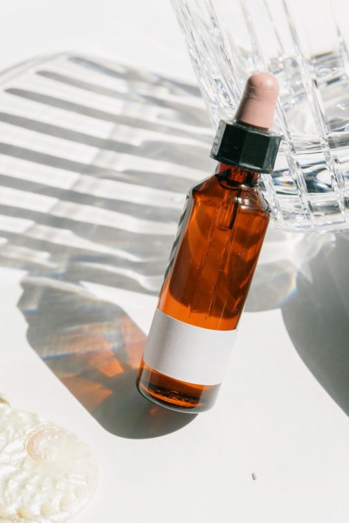 Sophisticated amber glass bottle with a dropper on a light background, ideal for beauty and skincare themes.