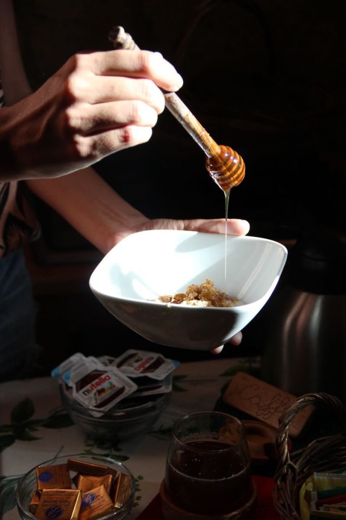 A close-up of honey being drizzled over breakfast cereal in a bowl, creating a delicious morning meal.