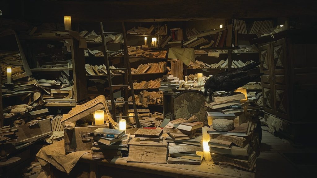 A dimly lit study filled with books and candles