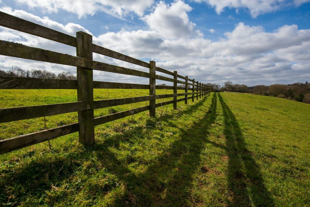 a long wooden fence in a grassy field